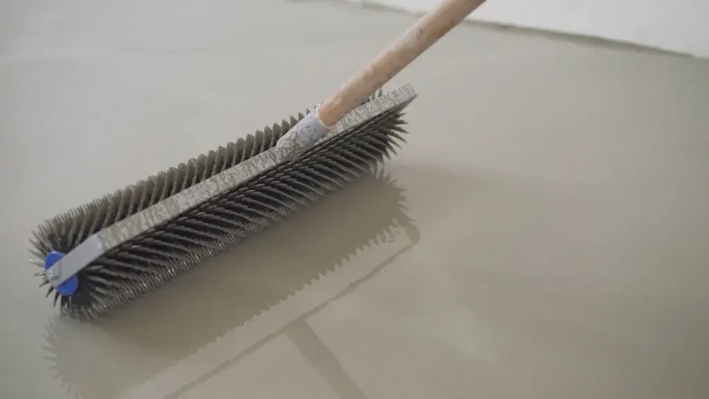 Spiked roller applying microplastic-free coatings on concrete floor for smooth, durable finish.