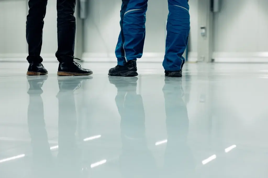 Workers standing on a smooth industrial floor protected with a durable antimicrobial protective coating designed for industrial surface protection.