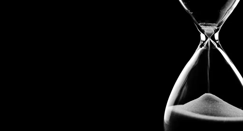 Black-and-white hourglass representing how contamination risks in industrial coating systems develop long before visible failure is detected.